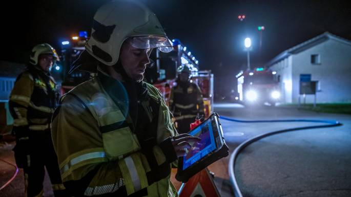 Feuerwehrmann im Einsatz mit einem mit Fotokit gefesselten UAV-Kommando-Tablett für die Wahrnehmung thermischer Situationen aus der Luft